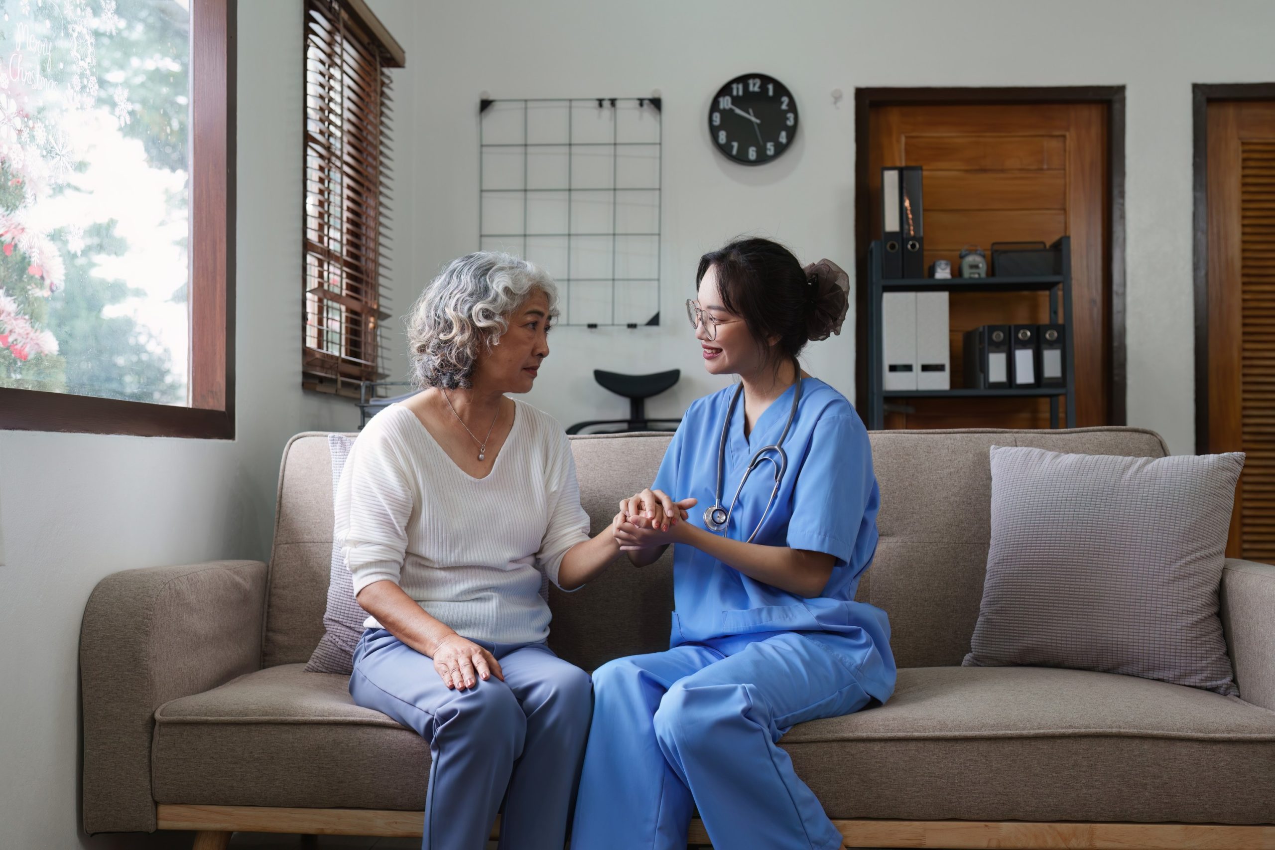 "Young Asian nurse providing care to elderly patient"