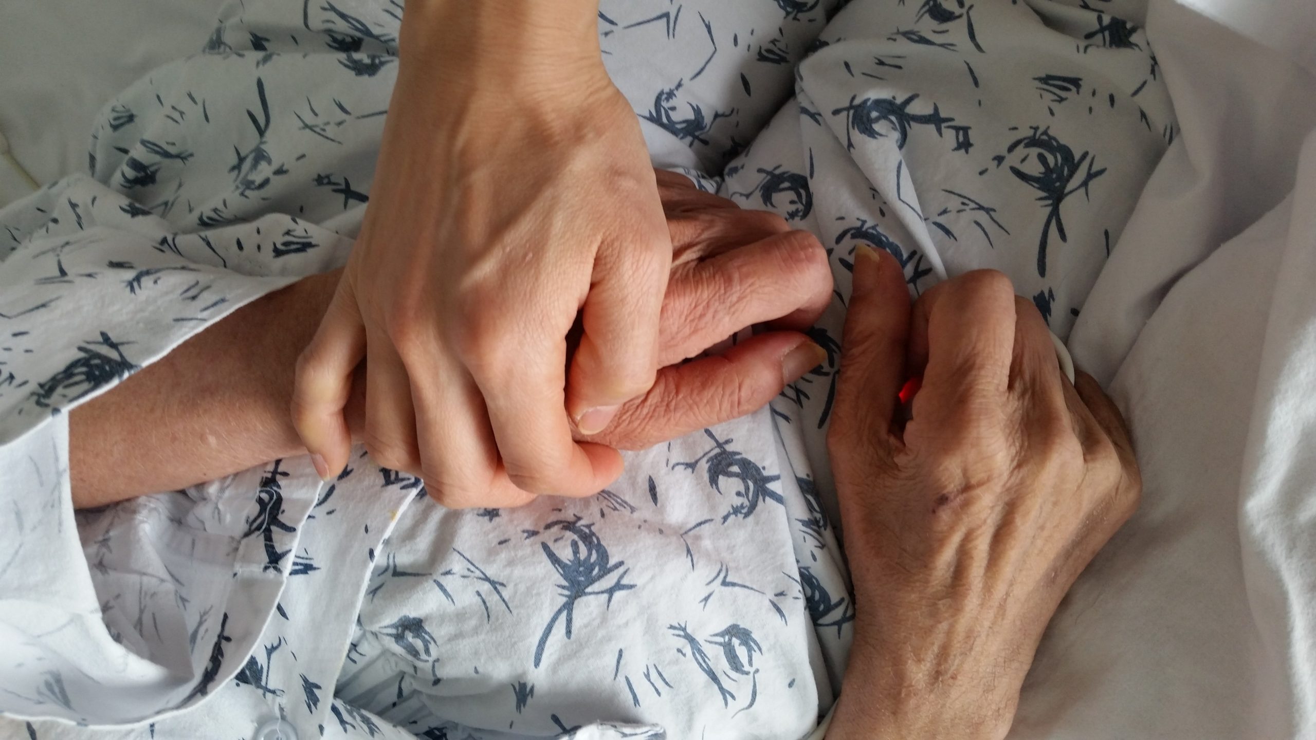 Elderly couple holding hands receiving home care support
