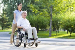 Nursing assistant providing care to wheelchair-bound man at home